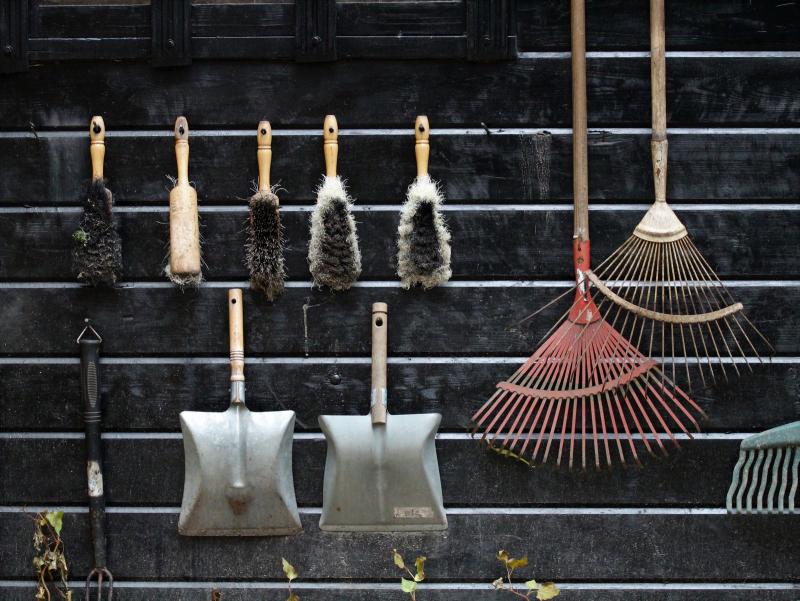 Des outils de jardin rangés et suspendus proprement sur un mur d'abri