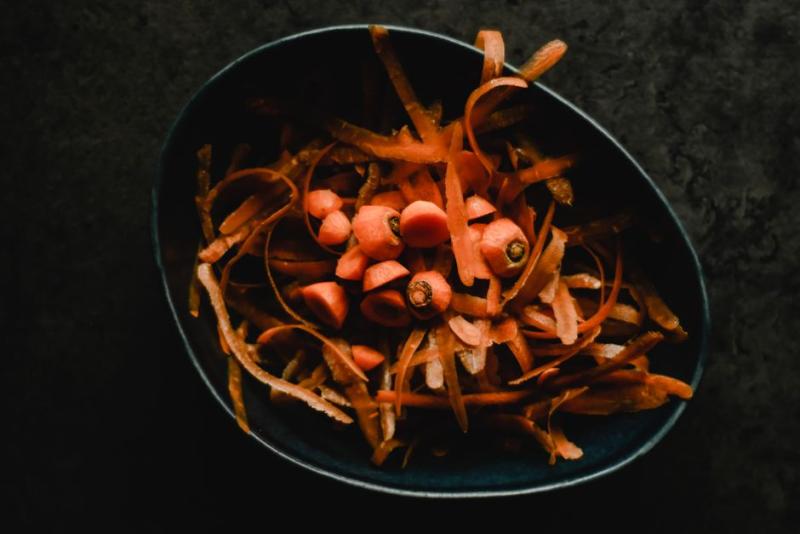 Épluchures de carottes et déchets de cuisine dans un bol, prêts pour le compost
