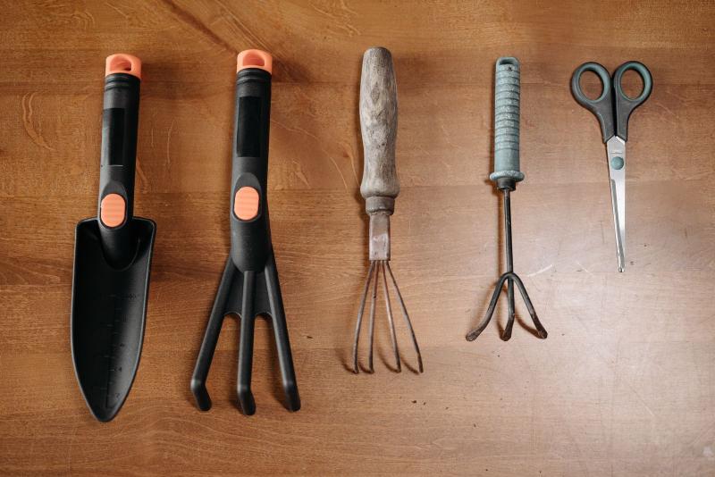 Des outils de jardinage de base posés sur une table : transplantoir, cultivateur et ciseaux